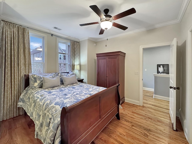 bedroom featuring baseboards, ornamental molding, visible vents, and light wood-style floors