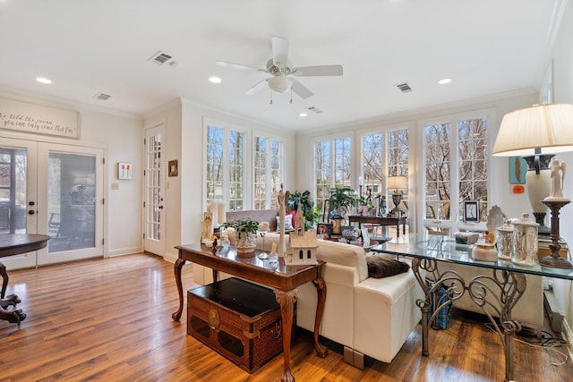 living room with crown molding, visible vents, and wood finished floors