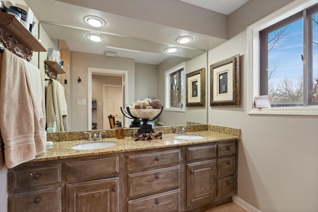 full bath with double vanity, baseboards, visible vents, and a sink