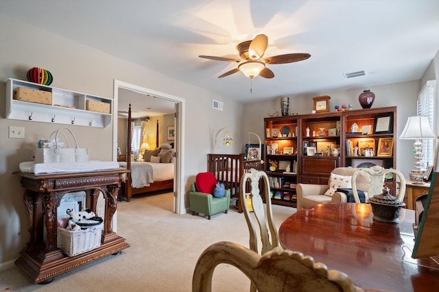 sitting room with a ceiling fan, a wealth of natural light, visible vents, and light carpet