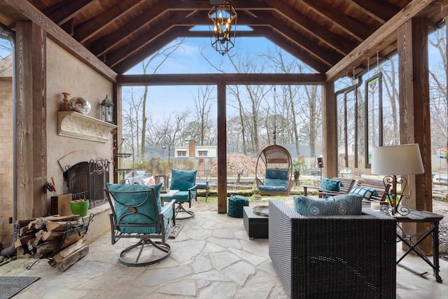 sunroom with a chandelier, a large fireplace, wooden ceiling, and vaulted ceiling with beams