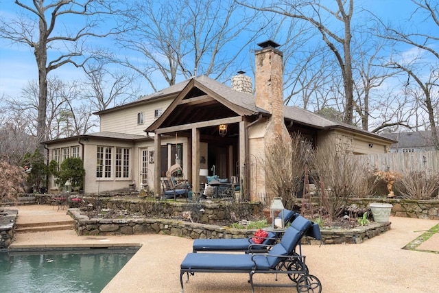 rear view of property with a patio area, a chimney, fence, and an outdoor pool