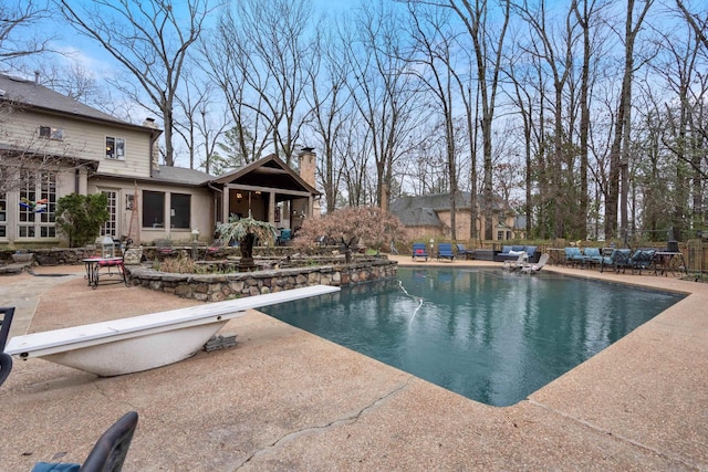 outdoor pool featuring a diving board and a patio