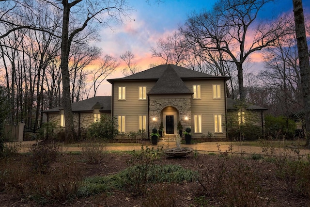 french country home featuring stone siding and roof with shingles