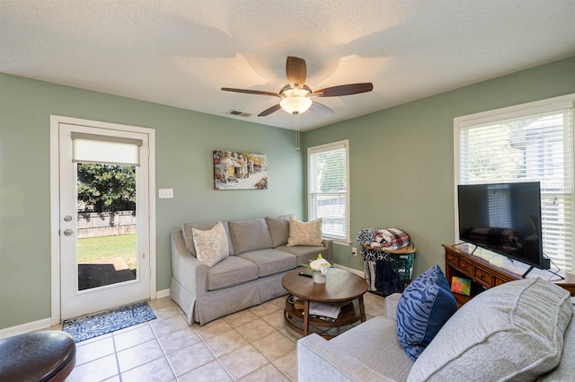 living area featuring light tile patterned floors, a textured ceiling, visible vents, and a ceiling fan