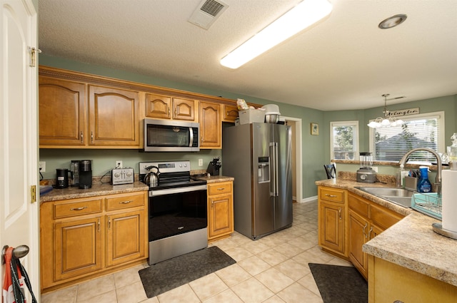 kitchen with visible vents, appliances with stainless steel finishes, light countertops, pendant lighting, and a sink