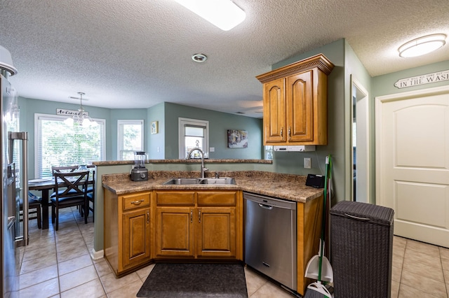 kitchen featuring pendant lighting, brown cabinets, a sink, dishwasher, and a peninsula