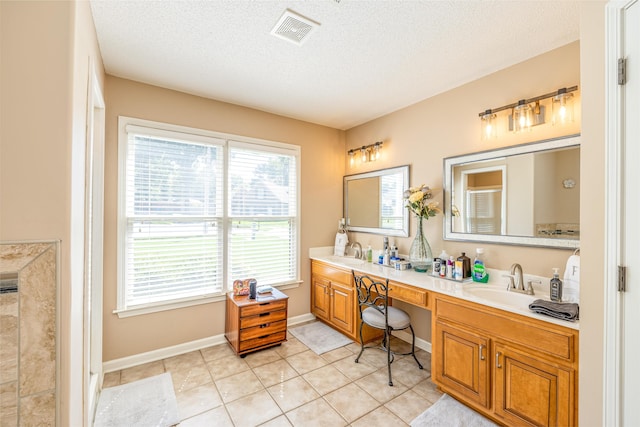 bathroom featuring visible vents, a sink, a textured ceiling, and double vanity