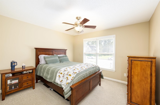 bedroom featuring light carpet, baseboards, and a ceiling fan