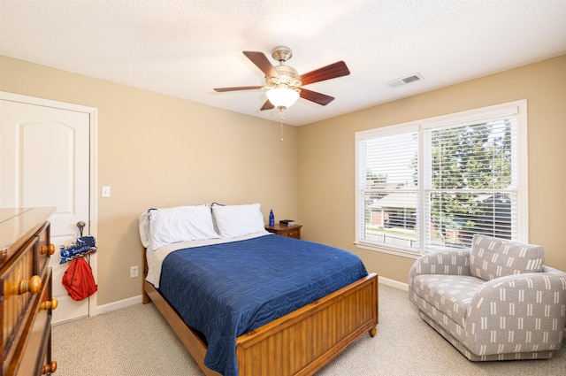 bedroom with baseboards, visible vents, a textured ceiling, and light colored carpet