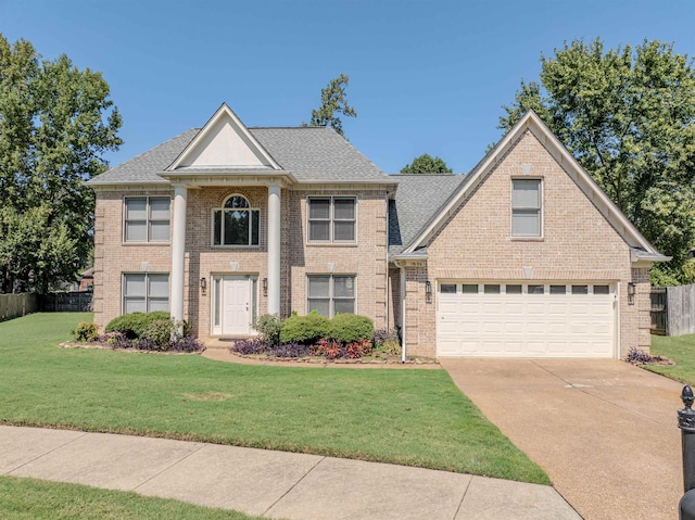 greek revival house featuring concrete driveway, an attached garage, fence, a front lawn, and brick siding