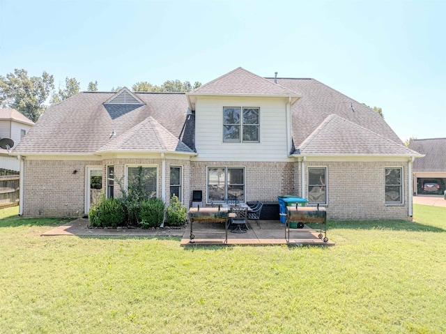 back of house featuring a shingled roof, brick siding, and a yard