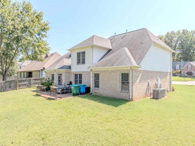 rear view of property featuring a yard, brick siding, and a patio