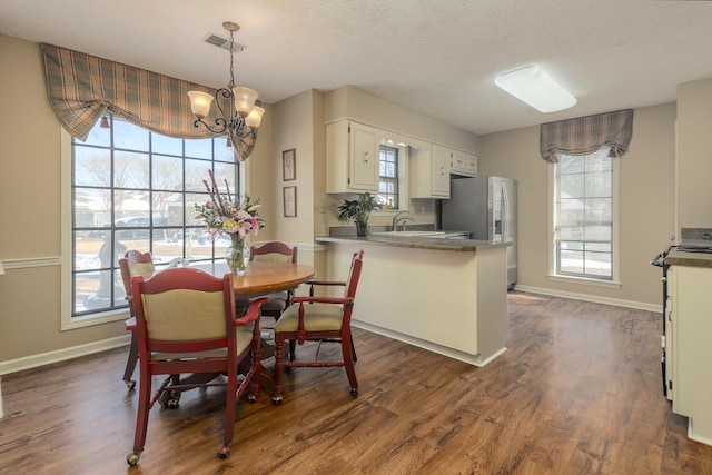 dining room with dark wood-style floors, a textured ceiling, and baseboards