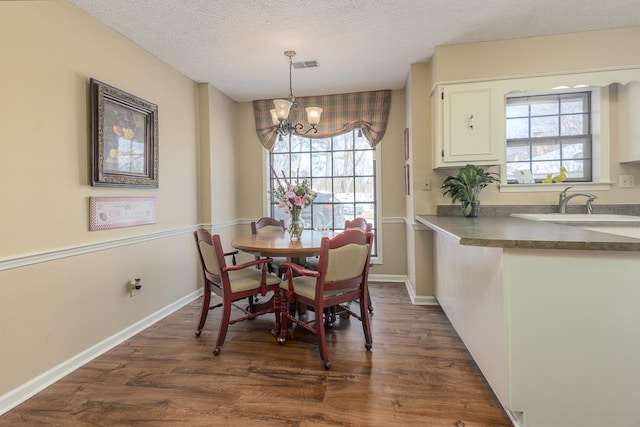 dining area with dark wood-style floors, a textured ceiling, plenty of natural light, and visible vents