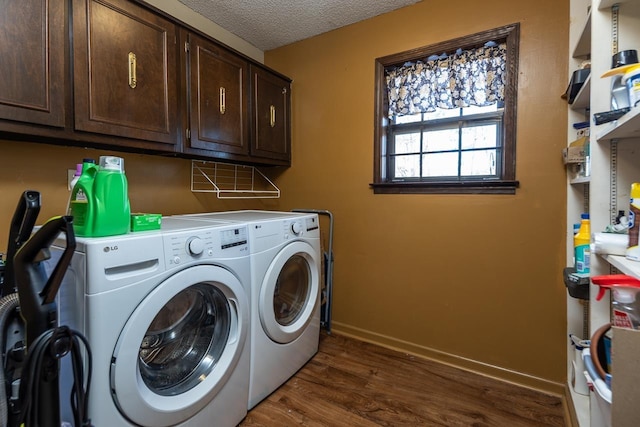 clothes washing area with dark wood-style floors, washer and clothes dryer, cabinet space, a textured ceiling, and baseboards