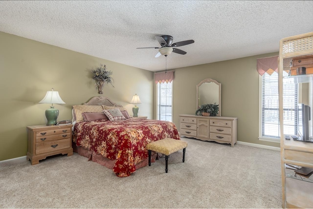 bedroom featuring light colored carpet, ceiling fan, a textured ceiling, and baseboards