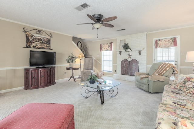 living room featuring visible vents, a textured ceiling, wainscoting, and a wealth of natural light