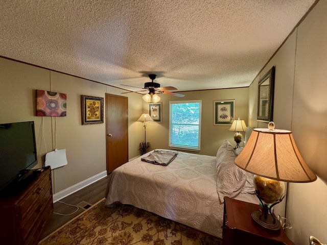 bedroom featuring ceiling fan, a textured ceiling, dark wood-type flooring, baseboards, and ornamental molding