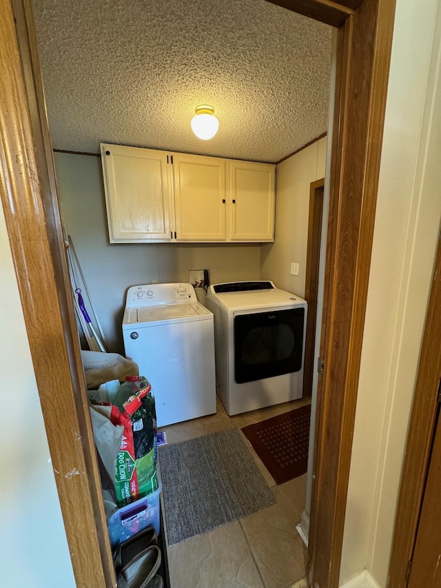 washroom featuring cabinet space, a textured ceiling, washing machine and clothes dryer, and light tile patterned flooring