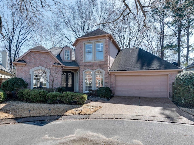 view of front facade with a garage, brick siding, a shingled roof, concrete driveway, and french doors