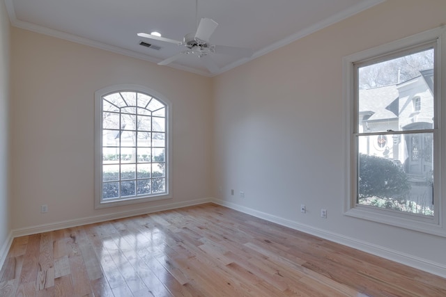 empty room featuring baseboards, visible vents, a ceiling fan, crown molding, and light wood-style floors