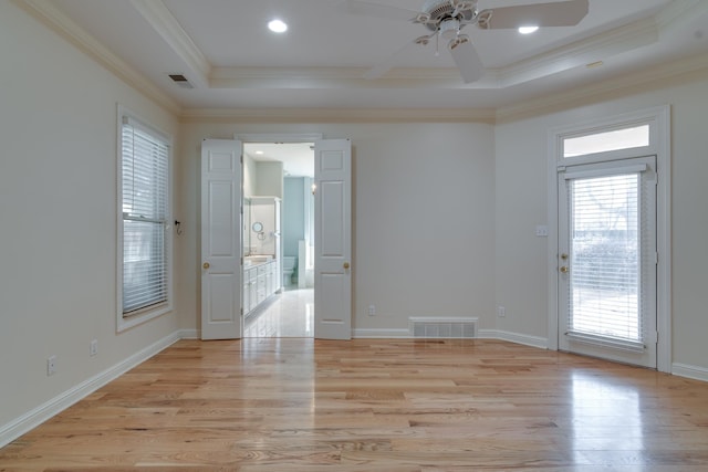 unfurnished room featuring light wood-style floors, visible vents, a tray ceiling, and ornamental molding