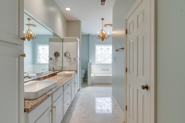 bathroom featuring a garden tub, a notable chandelier, visible vents, and a sink