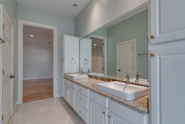 bathroom with recessed lighting, a sink, baseboards, and double vanity