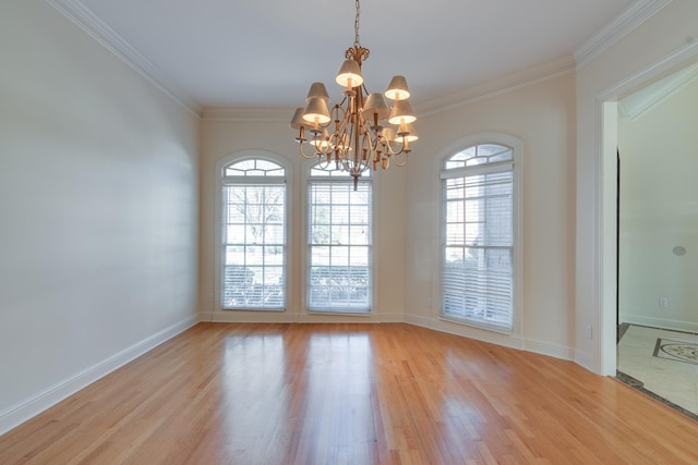 spare room featuring light wood-style floors, baseboards, ornamental molding, and a notable chandelier