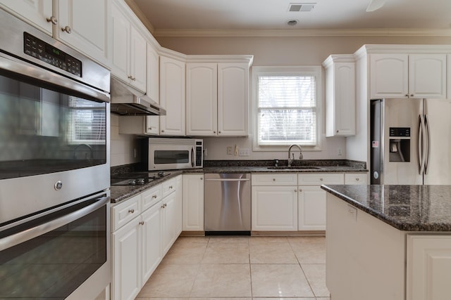 kitchen with appliances with stainless steel finishes, white cabinets, a sink, dark stone countertops, and under cabinet range hood