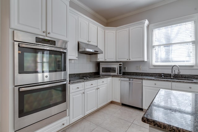 kitchen featuring stainless steel appliances, tasteful backsplash, white cabinetry, a sink, and under cabinet range hood