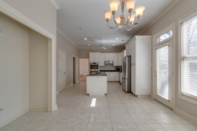 kitchen featuring a center island, stainless steel appliances, dark countertops, ornamental molding, and white cabinets