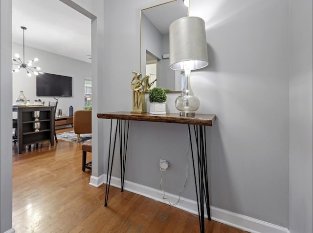 interior space with a notable chandelier, baseboards, and wood finished floors