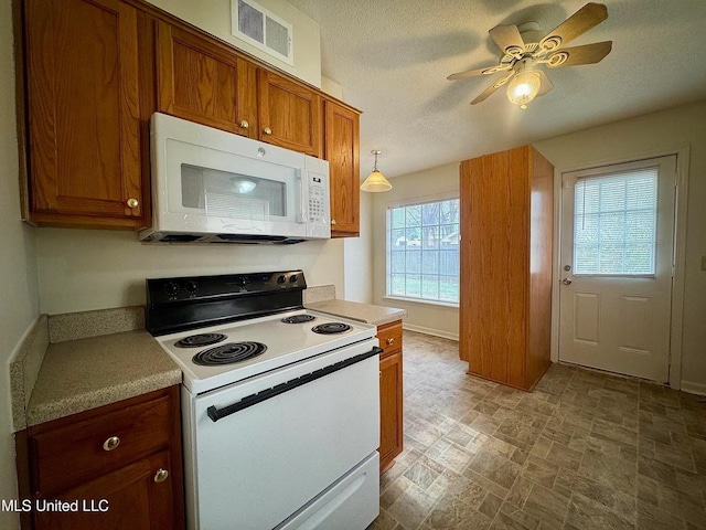 kitchen featuring brown cabinets, light countertops, visible vents, a textured ceiling, and white appliances