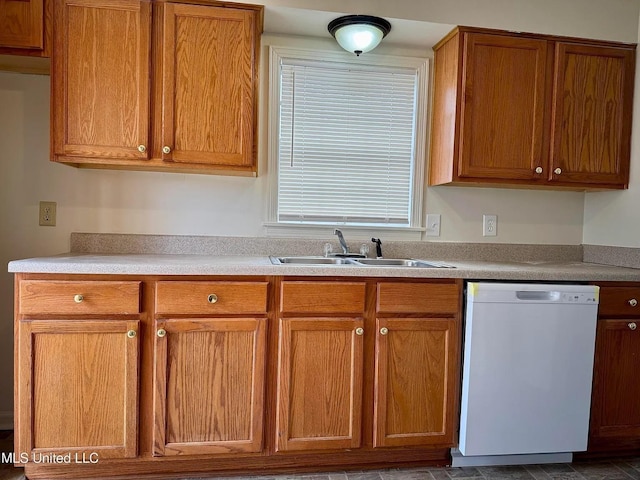 kitchen with brown cabinetry, light countertops, dishwasher, and a sink