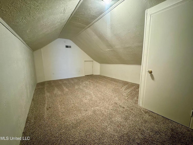 bonus room featuring visible vents, a textured wall, vaulted ceiling, a textured ceiling, and carpet flooring