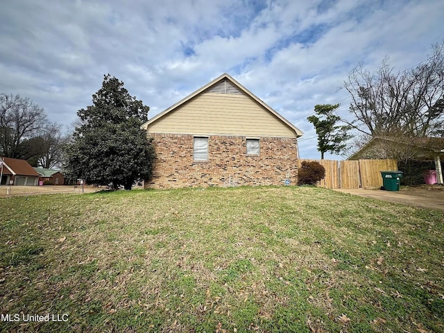 view of property exterior featuring a yard, brick siding, and fence