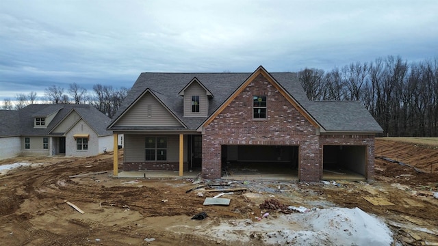 view of front of home featuring an attached garage, a shingled roof, and brick siding