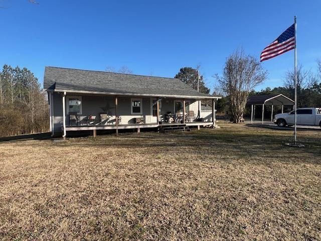 back of property with a yard and a carport