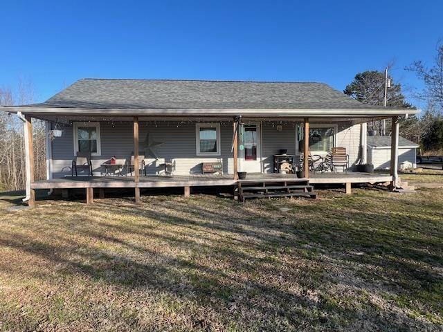 rear view of house featuring roof with shingles and a yard