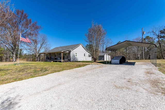 view of side of property with a porch, gravel driveway, a lawn, and a carport