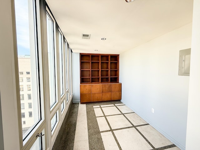 spare room featuring built in shelves, visible vents, electric panel, and baseboards