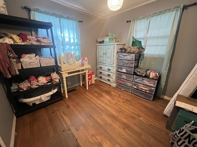 bedroom with ornamental molding and wood finished floors