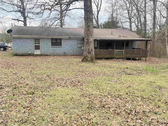 back of house featuring metal roof, a yard, and brick siding