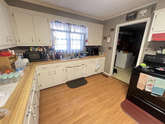 kitchen with white cabinets, light countertops, a sink, and black / electric stove