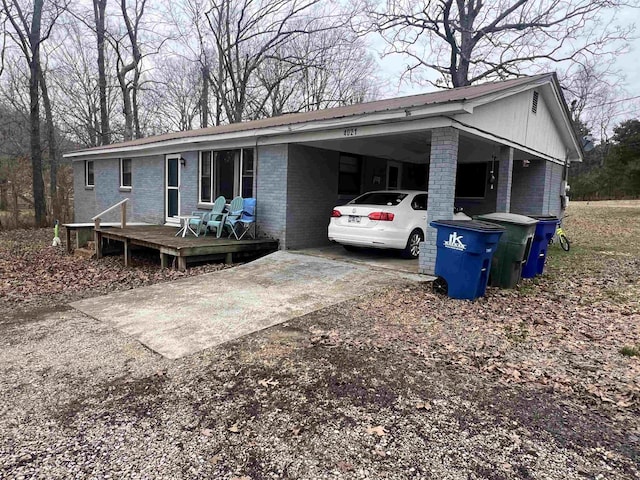 view of front of home with driveway, a carport, and brick siding