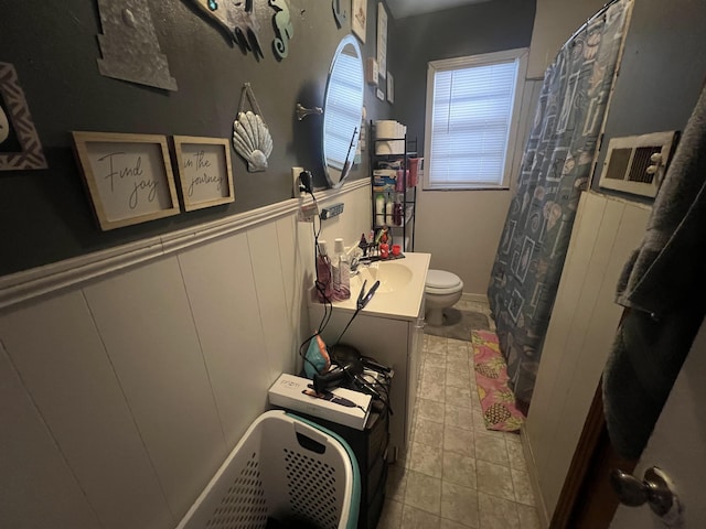 full bathroom with wainscoting, a decorative wall, vanity, and toilet