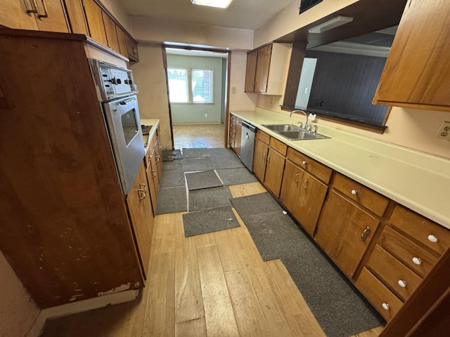 kitchen featuring brown cabinetry, dark wood-style flooring, light countertops, and a sink