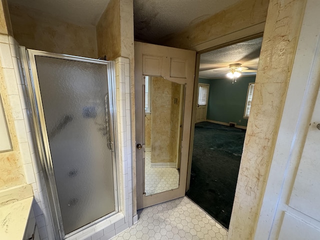 full bath featuring a shower with door, ceiling fan, and a textured ceiling